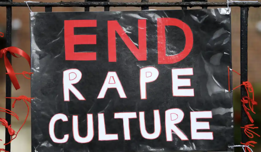 A black and read sign reading: "end rape culture" against the falling rape prosecutions