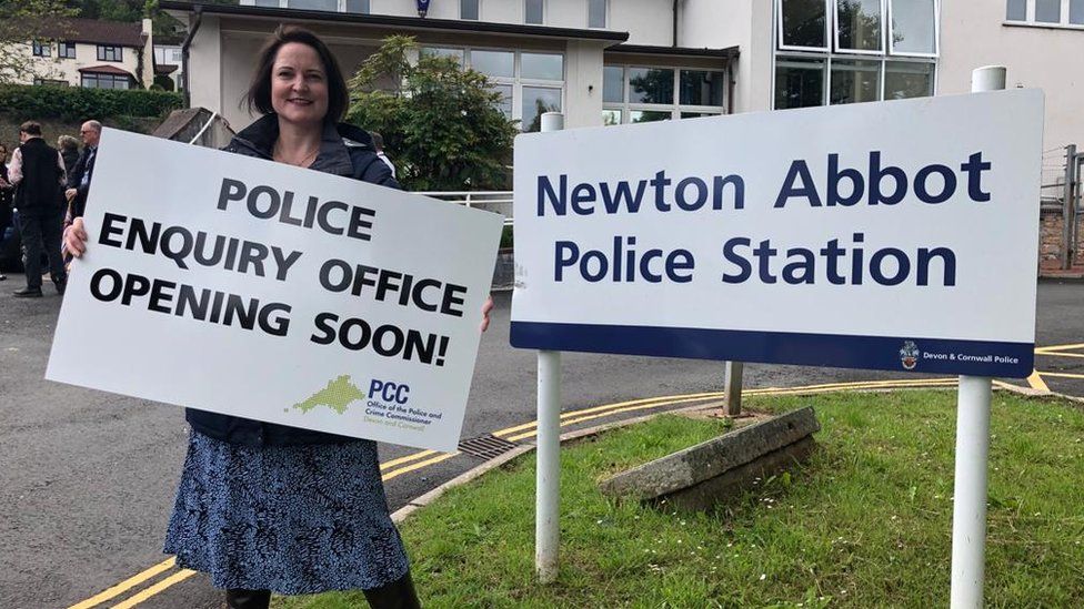 Woman stood with sign saying Police enquiry office opening